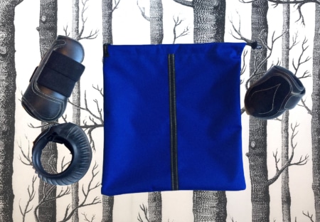 L'Ensemble « sport chic », un sac bleu à fermeture éclair noire, est mis en évidence parmi les équipements de protection sur un fond noir et blanc à motifs d'arbres.