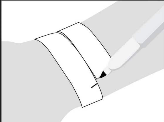 Illustration d'une personne marquant un papier enroulé autour de son poignet avec un stylo, évoquant la précision et le dévouement d'un cavalier expérimenté organisant ses accessoires d'équitation.
