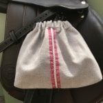 La Housse d’étriers « sport chic » est une pochette à cordon d’inspiration Cavalier à rayures rouges et blanches, qui ajoute une touche élégante à votre tapis de selle. Elle complète n’importe quel ensemble en cuir foncé, parfaite pour les passionnés d’équitation.