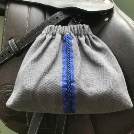 Les "Housses d’étriers « sport chic »" en gris avec une touche bleue complètent élégamment la selle en cuir foncé, ce qui en fait un accessoire idéal pour tout cavalier.