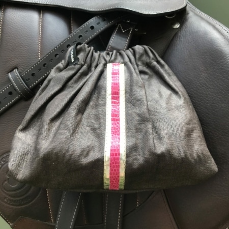 Les Housses d’étriers « sport chic » présentent une pochette à cordon à rayures roses et blanches sur un sac en cuir foncé, ce qui en fait un accessoire élégant pour tout cavalier.