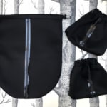 Sur un fond à motifs d'arbres, trois Housses d'étriers "Sport", des sacs à cordon noirs à rayures bleues et noires inspirés du cheval, ajoutent une touche élégante à cet accessoire de charme.